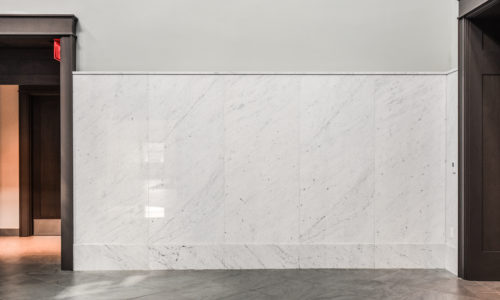 Carrara marble wall panels with a gray tile floor